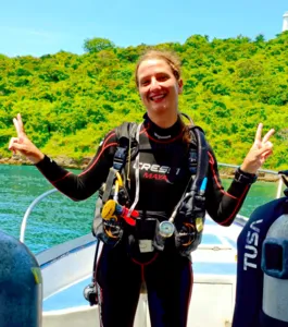 Scuba Froggy diver smiling with peace signs in scuba gear on a boat in Lombok, ready for macro dives at Pink Beach