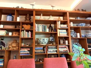 Rak kayu yang dipenuhi buku dan seramik di ruang bengkel yang nyaman di Singapura untuk membuat roti dan pencicah — bengkel di Singapura