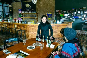 Beer tasting in a rustic bar in Shangri-La, with glasses on a table as a guide presents bottled brews to guests