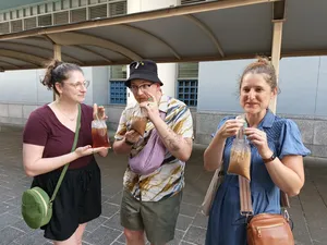 Three walkers holding takeaway drinks and posing outside in Geylang, Singapore on a private night walk — Singapore hidden gems