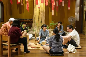 Small group tasting and learning at a wooden table as a host guides an agarwood scent workshop in Hanoi