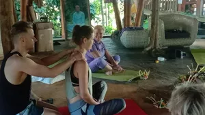 Group listening in a meditation circle at Omunity Bali in Bali, with flower offerings laid out on red mats beneath wooden beams