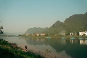 Slow riverside walk in Phong Nha as travellers head along a calm river bordered by lush banks and tall green hills