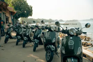 Skuter Vespa klasik berjajar di jalan tepi laut Hoi An saat tur berpemandu