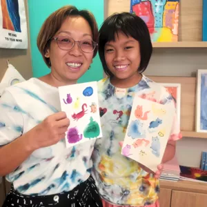 Art For Good art therapy in Singapore: two participants proudly holding painted animal cards during workshops in Singapore