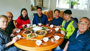 Communal lunch at a round table with bowls and chopsticks indoors during a countryside trek with The Bivou Lijiang in Lijiang