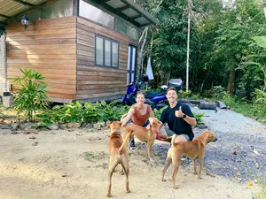 Kebun Lidstari permaculture farmstay in Langkawi: people smiling with dogs outside a wooden cabin in the greenery