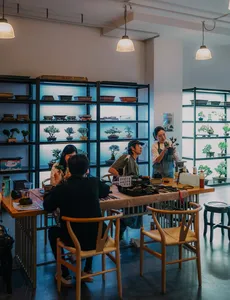 Bonsai workshop class in Singapore with several people working at tables beneath shelves of tropical trees — workshops in Singapore