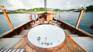 Circular jacuzzi on the wooden deck of a phinisi sailing past the coastline on a Komodo luxe cruise in Labuan Bajo