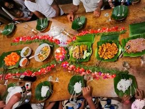 Hands preparing ritual plates with green leaves and flower petals on a wooden table during cleansing at Omunity Bali, Bali