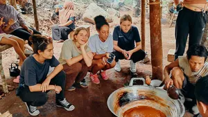 People gather around a large cooking pot outdoors in Lombok during the Lombok Forest Tour’s included cooking experience