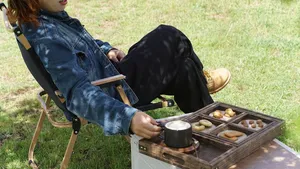 Outdoor coffee break at the Lijiang coffee estate: seated guest stirs snacks on a portable grill beside a tray of breads