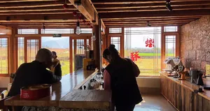 Silhouetted guests learning about Yunnan coffee at a family workshop in Lijiang, seated by large roasting and brewing counter