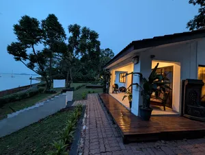 Dusk view of a wooden deck with chairs beside large windows, garden paths leading to the sea at a Singapore 2D1N farmstay