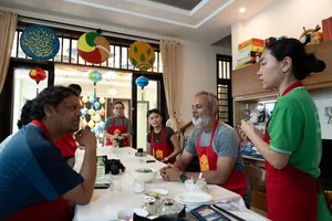 客人们围坐在会安 Jolie Cooking Class 的餐桌旁，在家庭式厨房里学习制作越南菜