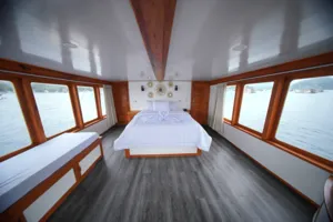 Spacious onboard cabin with a neatly made double bed and decorative wall lights on a join-in 3D2N Komodo trip, near Komodo Island