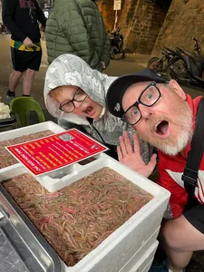 Travellers grinning at a Hanoi street food stall, leaning over an ice tray of ingredients during a guided food adventure