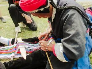 Tibetan artisans’ hands working colourful textiles on a loom during a homestay craft session in Shangri-La