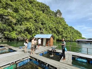 Small group gathering on a wooden jetty near a riverside hut in Langkawi before launching on a Selva-led kayak trip in Kilim