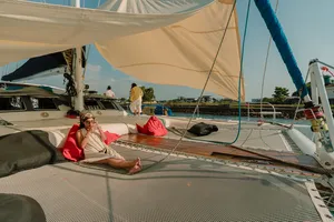 Travellers relaxing on the upper deck with sail canopies on a catamaran near Kota Kinabalu’s coastline as the cruise continues