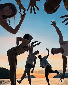 Friends jumping on the beach at sunset during a 2D1N Surin Island beach camping trip with Moken guides near Khao Lak