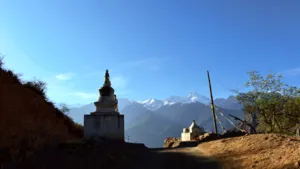 Tibetan stupa shrine on a hilltop with Meili Snow Mountain peaks in the distance beneath a clear blue sky