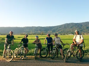 Cyclists pausing with their bikes on a scenic road through Langkawi countryside during a villages, markets and jetty ride