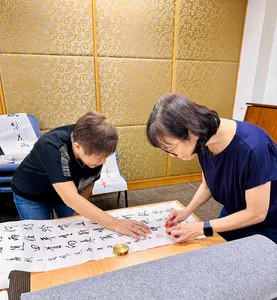 Learners practise Chinese brush calligraphy at a table in a Singapore studio, writing a blessing at calligraphy workshops in Singapore