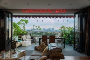 View into a cosy Singapore loft with string lights and city skyline through open doors, plants by the dining table