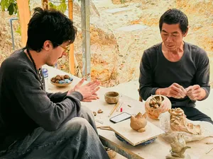 朋友们在大理一座古老陶村探访时,坐在陶艺工作台前塑形并修整陶土作品