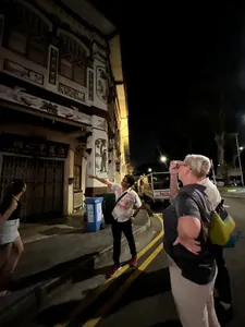 Guide gesturing along a dim Geylang street during Indie Singapore Tours’ private night walk, with visitors looking on, Singapore hidden gems
