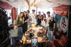 Group smiling around coffee and bagel brunch tables under a tent canopy during hands-on coffee roasting workshops in Singapore