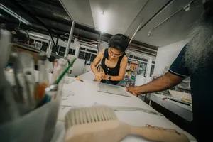 Glass centrepiece workshop in Singapore: a guest uses a tool to shape clear glass on a studio workbench, workshops in Singapore
