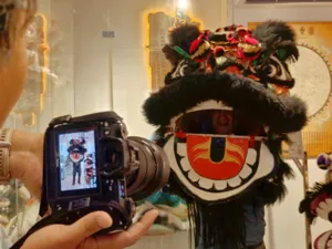 Close-up filming moment in a Ho Chi Minh City kung fu and lion dance workshop, with a lion head puppet filling the frame