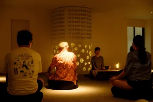 Participants sit on the floor as a host presents agarwood scents in a lantern-lit workshop room in Hanoi