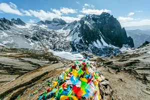 Colourful prayer flags overlooking snow-capped peaks and a valley in Shangri-La, along the Tiger Leaping Gorge trek