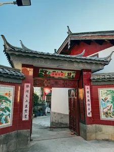 Traditional Naxi-style guesthouse entrance in Lijiang, Yunnan, with red door panels, ornate carvings and tiled roof eaves