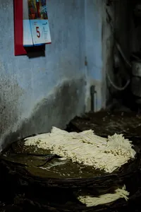 Mounds of pale noodles or dough strips laid out on a table in a narrow Hoi An backstreet stall at dawn