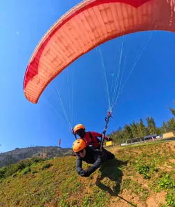 Tandem paragliders suspended under a red canopy above terraced valleys, preparing for lift-off in Vietnam Sapa