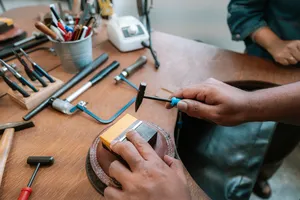 Hands shaping a silver ring with metal tools on a wooden bench at Fat Anvil Studios in Singapore â workshops in Singapore