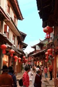 Lantern-lit walkway through Lijiang’s Shuhe Ancient Town, with Naxi-style buildings and people strolling along the lane