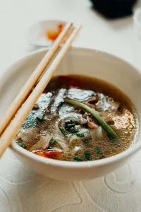 在会安 Jolie Cooking Class 的当地家庭厨房里烹制的一碗热气腾腾的越南汤，配有香草和筷子
