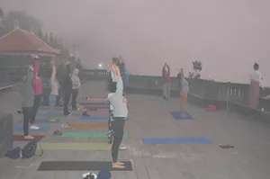 Outdoor yoga class on a foggy hillside terrace in Indonesia, travellers stretching on floor mats in a calm morning session