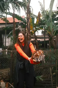 Smiling woman holding a large clay bowl among palms and greenery at a workshop in Hoi An’s countryside at dawn