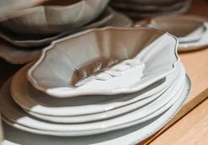Stack of white embossed ceramic plates on a wooden table, created with antique-style detailing for everyday dining in Singapore