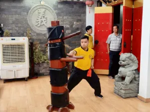 Kung fu and lion dance practice in a Ho Chi Minh City studio, learners working around a black-and-red wooden training dummy