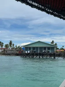 Banglo air berbung bumbung biru kehijauan dengan dek panjang di atas laut jernih Semporna, bersama Bigfin Divers