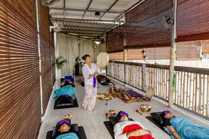 Lying guests in a guided sound healing session at ADDA Yoga in Canggu, with bronze singing bowls along the rooftop