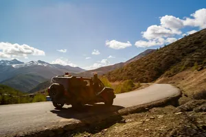 Off-road tour jeep driving along a winding mountain road with wide valleys on the 6-day Shangri-La Loop with a Tibetan guide