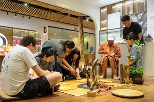 Guests kneel around a table of agarwood samples during a guided Hanoi workshop in a bright exhibition space
